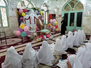تصویری از مراسم جشن تکلیف دانش‌آموزان دختر بخش درب‌گنبد با چادرهای سفید در صحن امامزاده محمد(ع) شهرستان کوهدشت