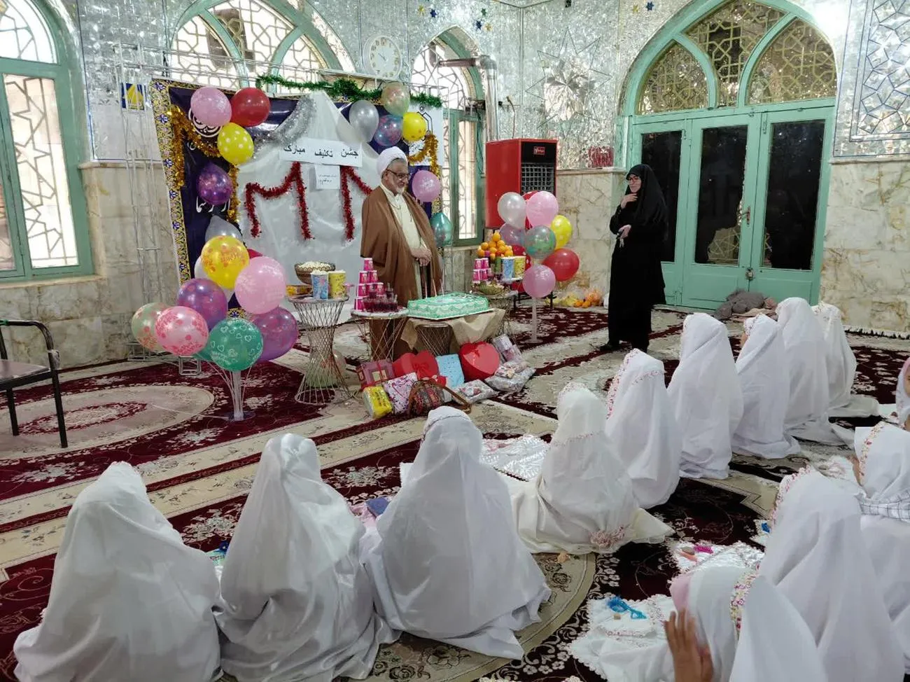 تصویری از مراسم جشن تکلیف دانشآموزان دختر بخش دربگنبد با چادرهای سفید در صحن امامزاده محمد(ع) شهرستان کوهدشت